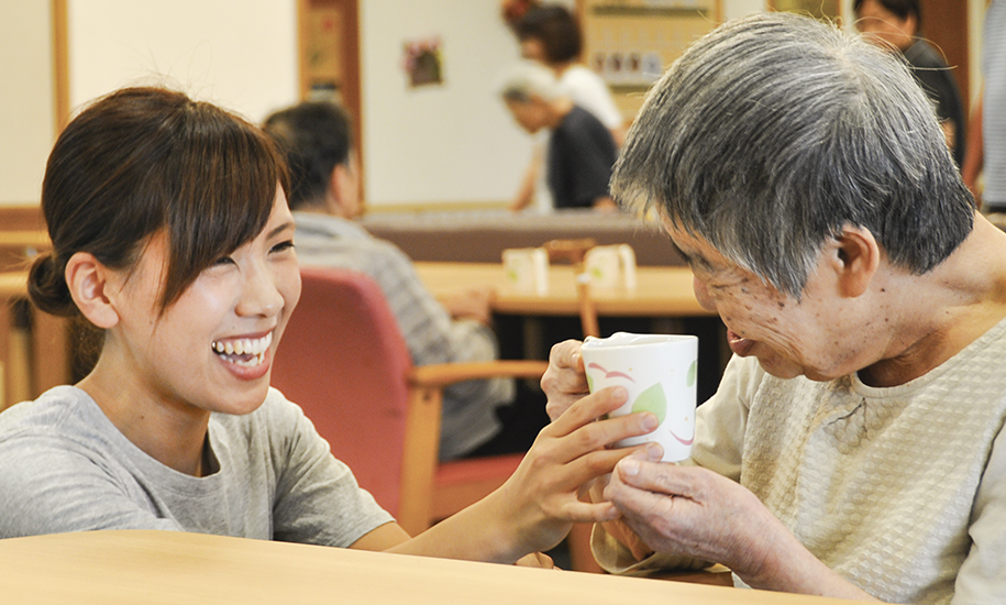 入居者様に飲み物を手渡す原田さんの写真